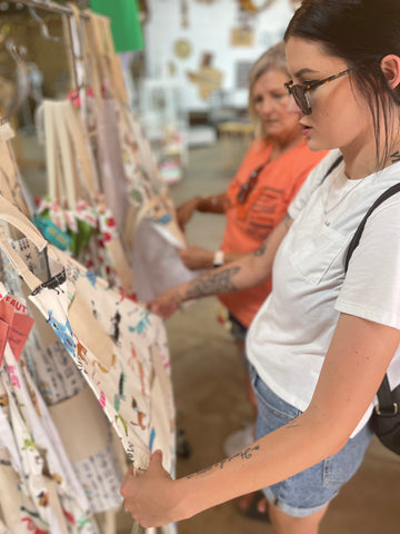 Two Medium Sized Ladies mother and daughter shopping for vintage style aprons at market in Texas