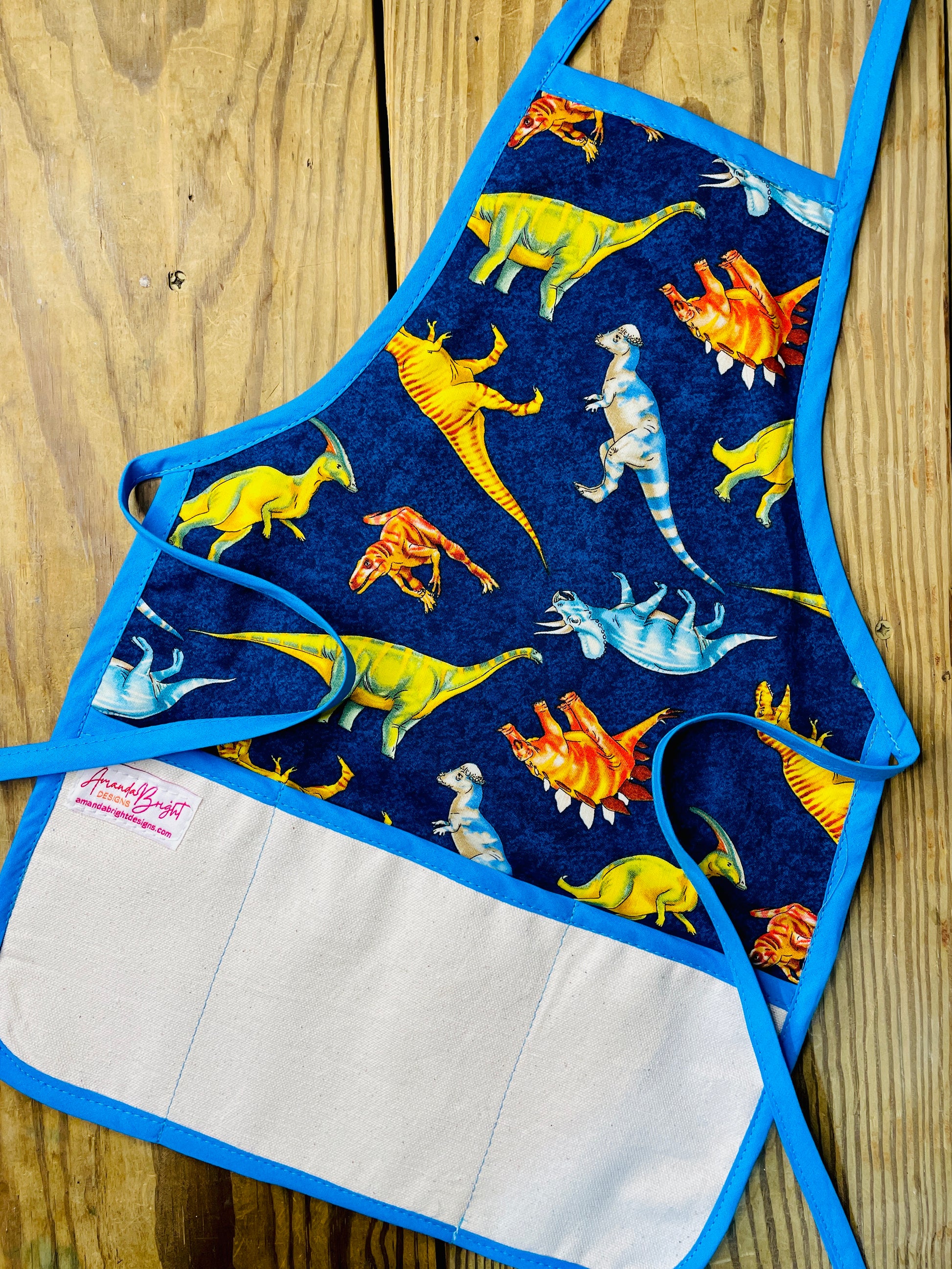 Amanda Bright Designs childrens dinosaurs apron stegosaurus tyrannosaurus triceratops extinct species for bake time play time blue apron strings