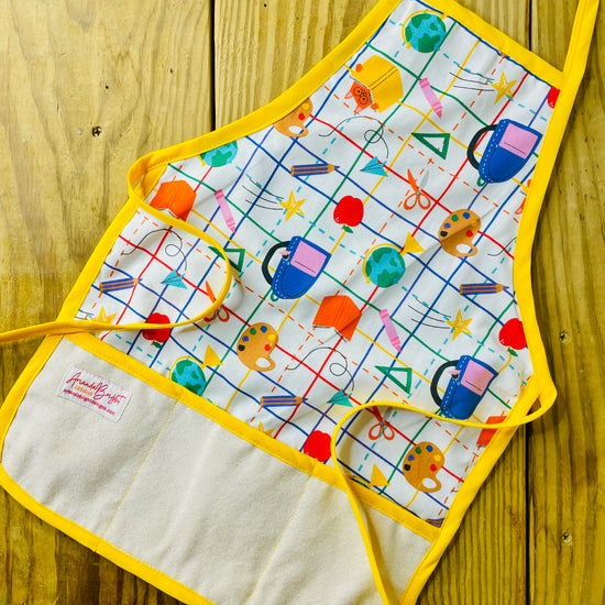 Amanda Bright Designs Children's School Daze Apron featuring artists palette world globe backpack books crayons pencils apple scissors school bus yellow trim
