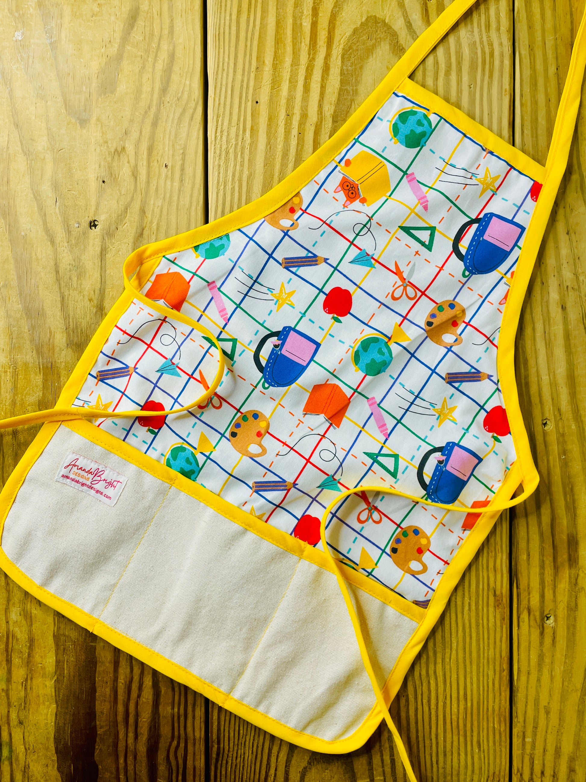 Amanda Bright Designs Children's School Daze Apron featuring artists palette world globe backpack books crayons pencils apple scissors school bus yellow trim