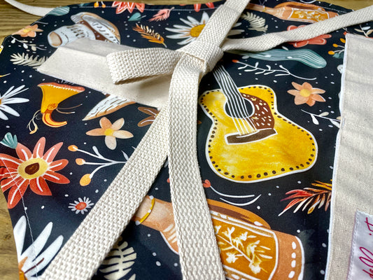 Amanda Bright Designs Delilah Apron with colorful western guitar cactus cowboy hat sunflower pattern on black background