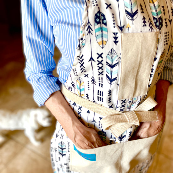 Two Medium Sized Ladies Candace hippie boho style kitchen baking cooking gardening apron feathers and arrows navy blue and gold on model closeup view