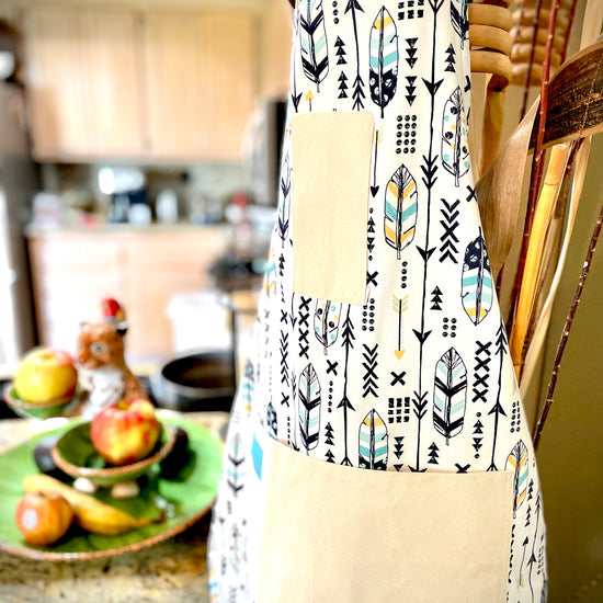 Two Medium Sized Ladies Candace hippie boho style kitchen baking cooking gardening apron feathers and arrows navy blue and gold hanging in the kitchen