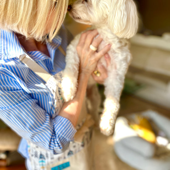 Two Medium Sized Ladies Candace hippie boho style kitchen baking cooking gardening apron feathers and arrows navy blue and gold on model with little dog