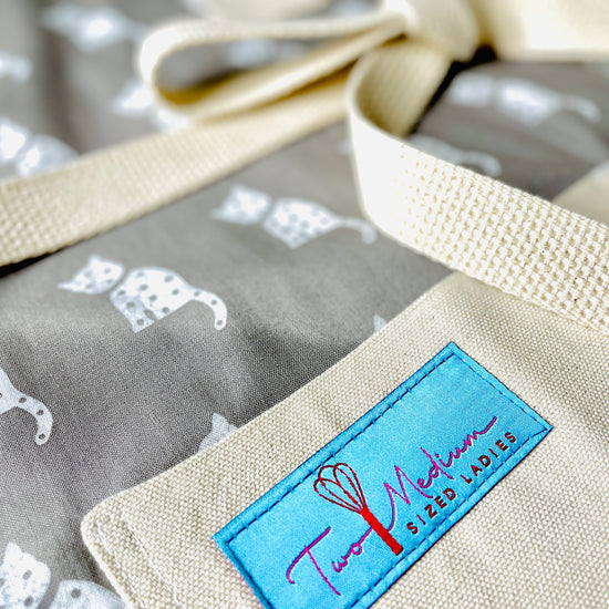 Two Medium Sized Ladies Cleo white cat gray background closeup view of kitchen animal lovers apron farmhouse style