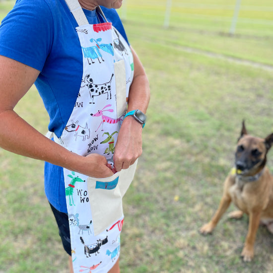 Two Medium Sized Ladies colorful playful dog apron Maribeth on dog trainer putting treats in pocket for pet