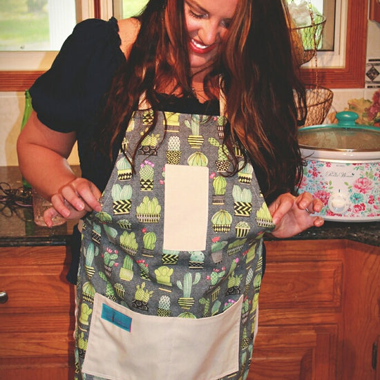 Two Medium Sized Ladies cactus kitchen apron lifestyle working in kitchen holding out sides Chloe