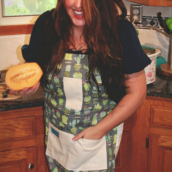 Two Medium Sized Ladies Chloe cactus apron woman wearing holding papaya in kitchen lifestyle