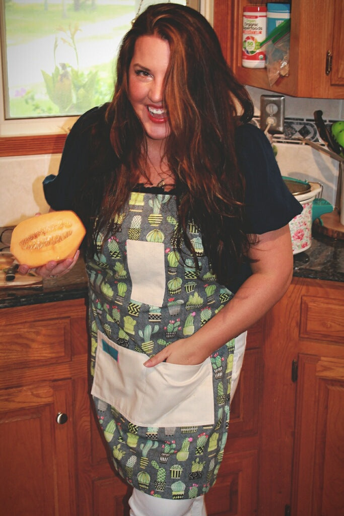 Two Medium Sized Ladies Chloe cactus apron woman wearing holding papaya in kitchen lifestyle