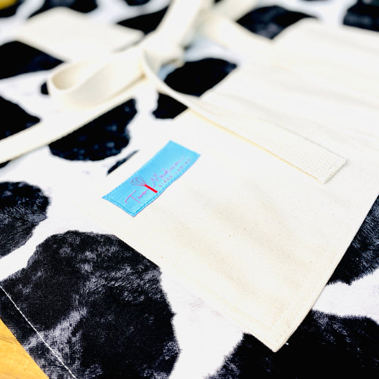 Two Medium Sized Ladies Susan Apron cowhide black and white holstein Susana Dickinson Lady of the Alamo modern farmhouse style close up view